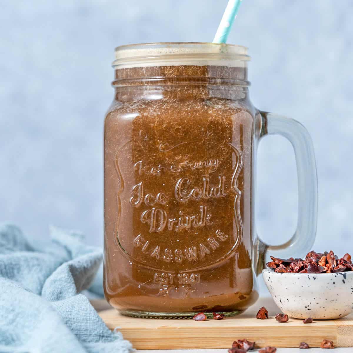 a mason jar filled with coffee protein shake with a straw in the jar.