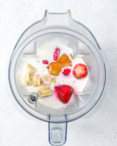 all ingredients for strawberry smoothie added to a blender.
