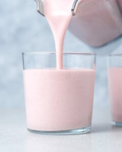 Pouring smoothie into a glass jar.