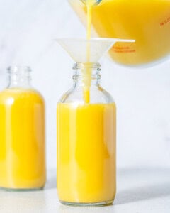 Pouring lemon ginger drink into a small bottle.