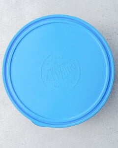 a bowl with the cheesecake dip covered with a blue lid.