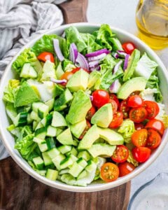 salad ingredients added to a bowl.