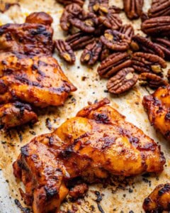 chicken cooked in a pan with pecans on the side.