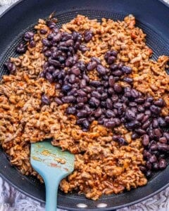 black beans added over seasoned ground beef in a skillet.