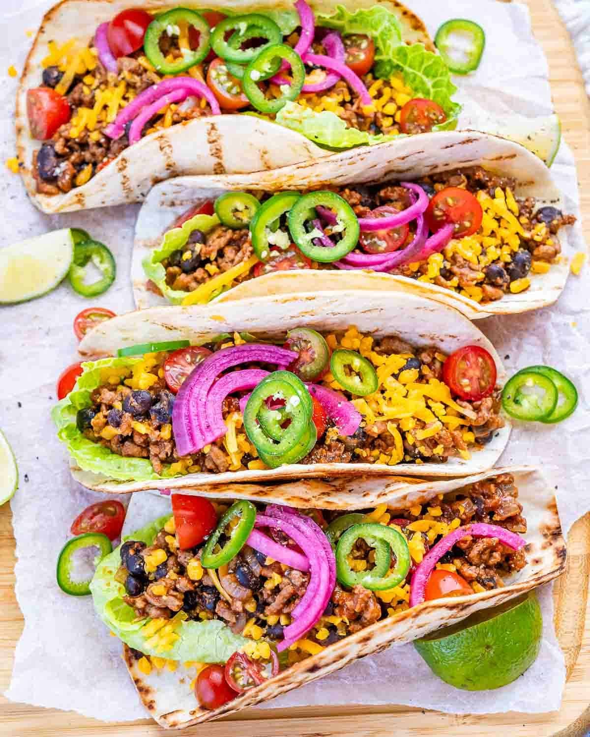 tacos laid out next to each other on a cutting board.