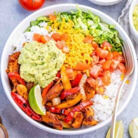 a bow with chicken fajitas served with rice, sauteed veggies, and guacamole.