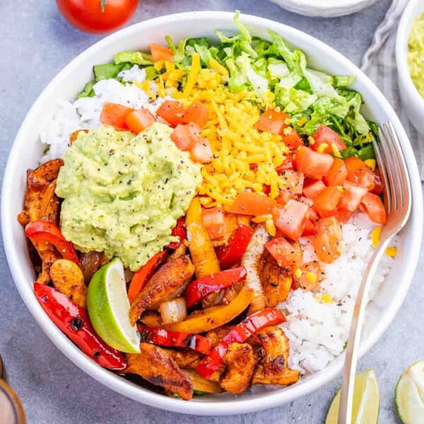 a bow with chicken fajitas served with rice, sauteed veggies, and guacamole.