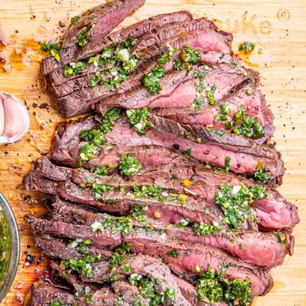 sliced steak topped with chimichurri sauce.