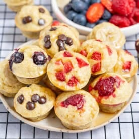 a small bowl filled with mini pancakes topped with berries.