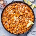 a large black skillet of chicken bites cooked in a peanut butter sauce.