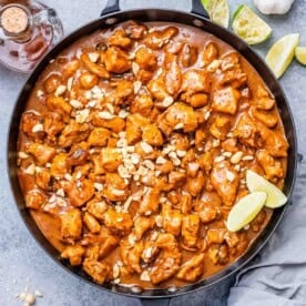 a large black skillet of chicken bites cooked in a peanut butter sauce.