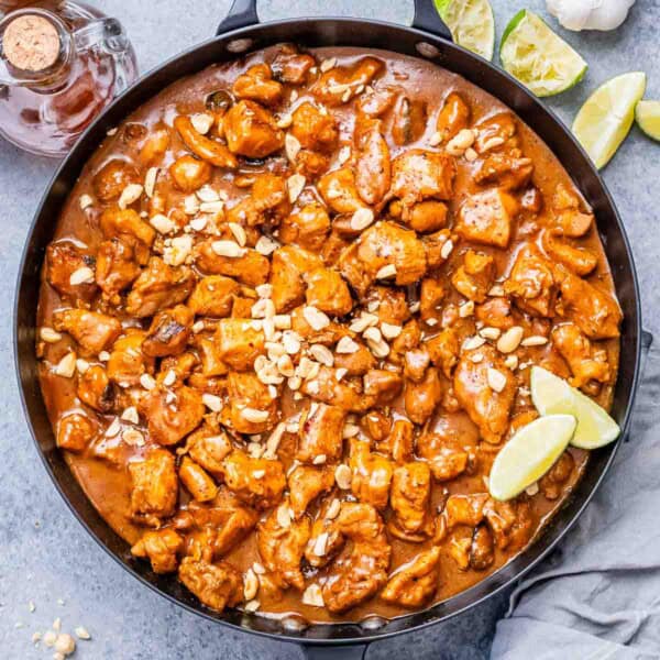 a large black skillet of chicken bites cooked in a peanut butter sauce.