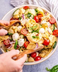 hand mixing the pasta salad.