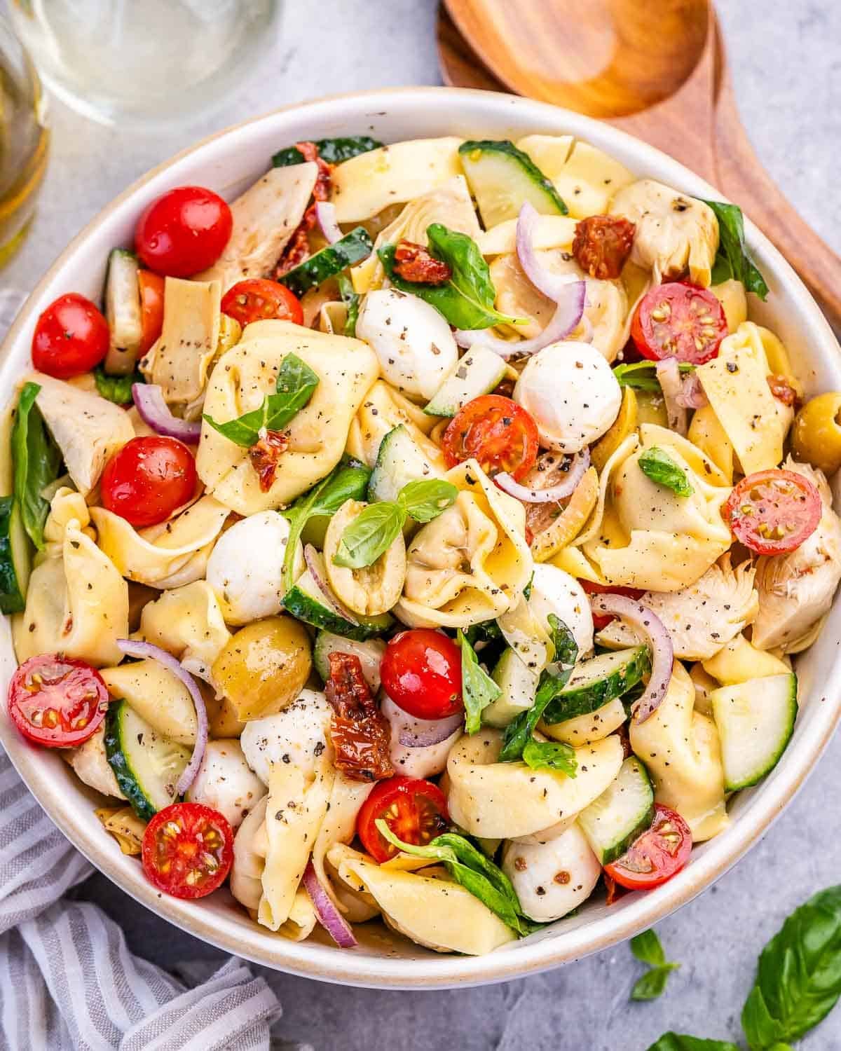 Tortellini pasta salad with veggies and mozzarella balls in a bowl.