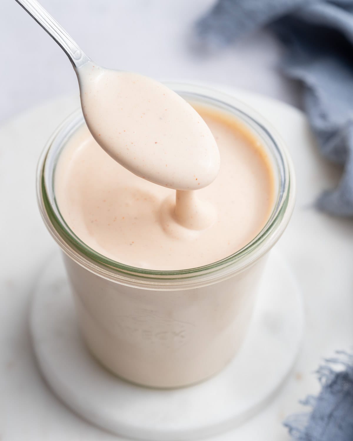 A jar of homemade yum yum sauce with a spoon drizzling it.
