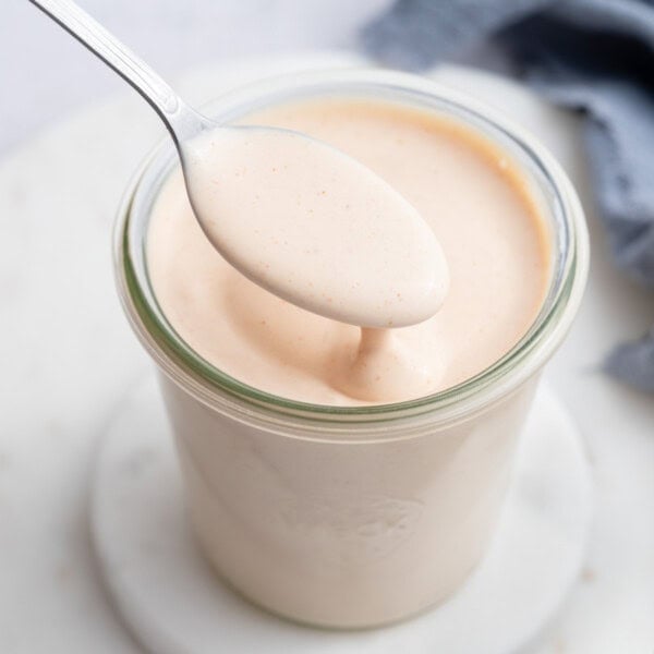 a jar with yum yum sauce a spoonful over the sauce in the jar.