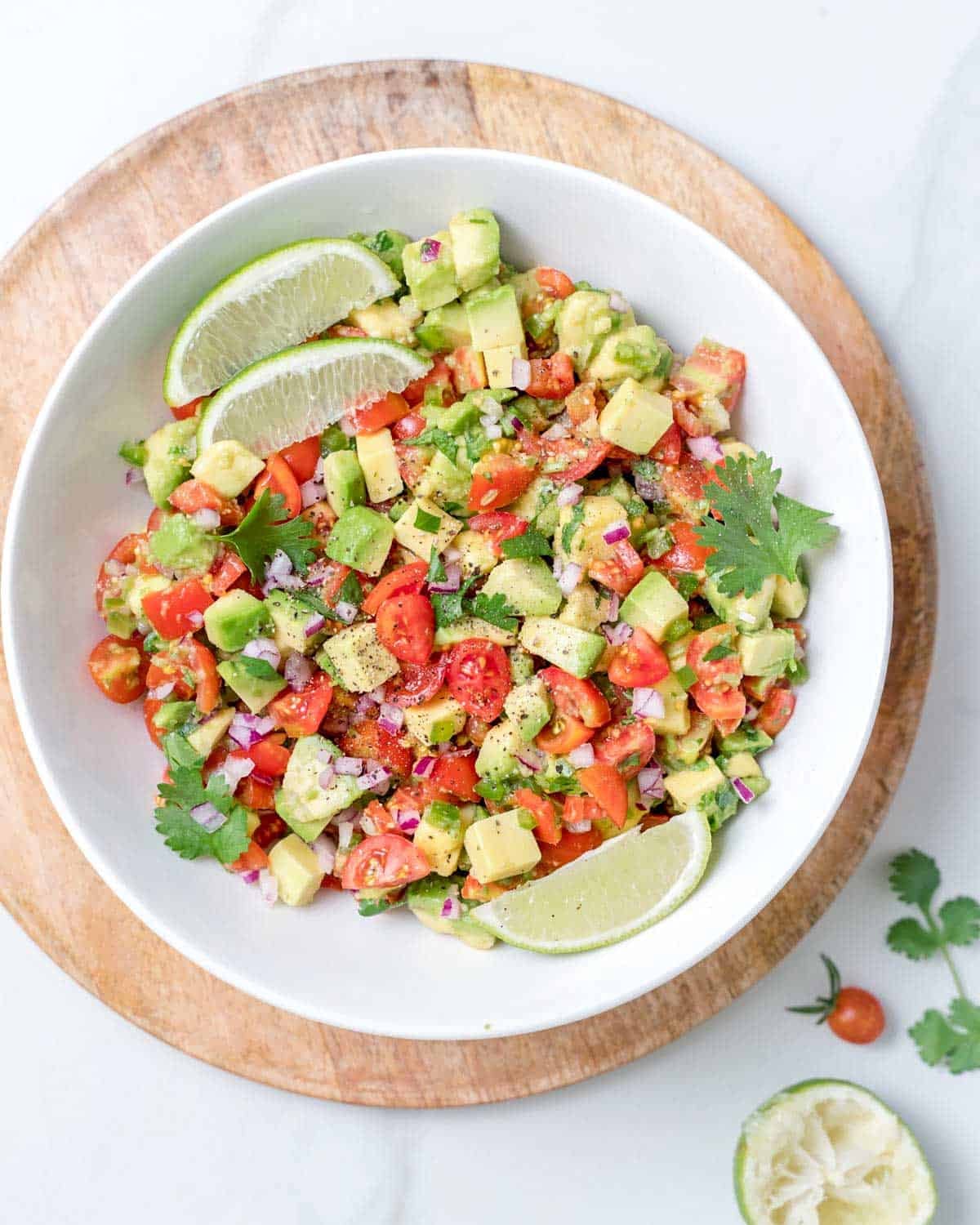 a bowl with avocado salsa topped with lime wedges.