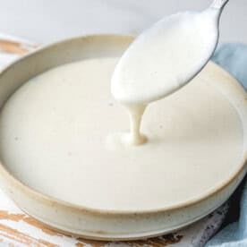 a bow with bechamel sauce and s spoon dipping in the sauce.