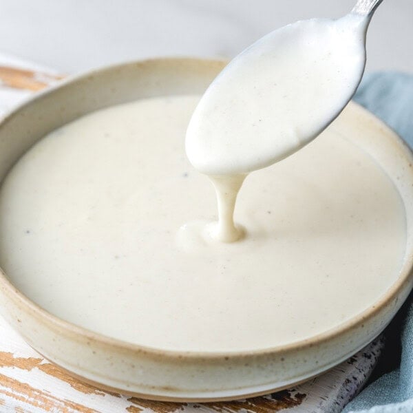 a bow with bechamel sauce and s spoon dipping in the sauce.