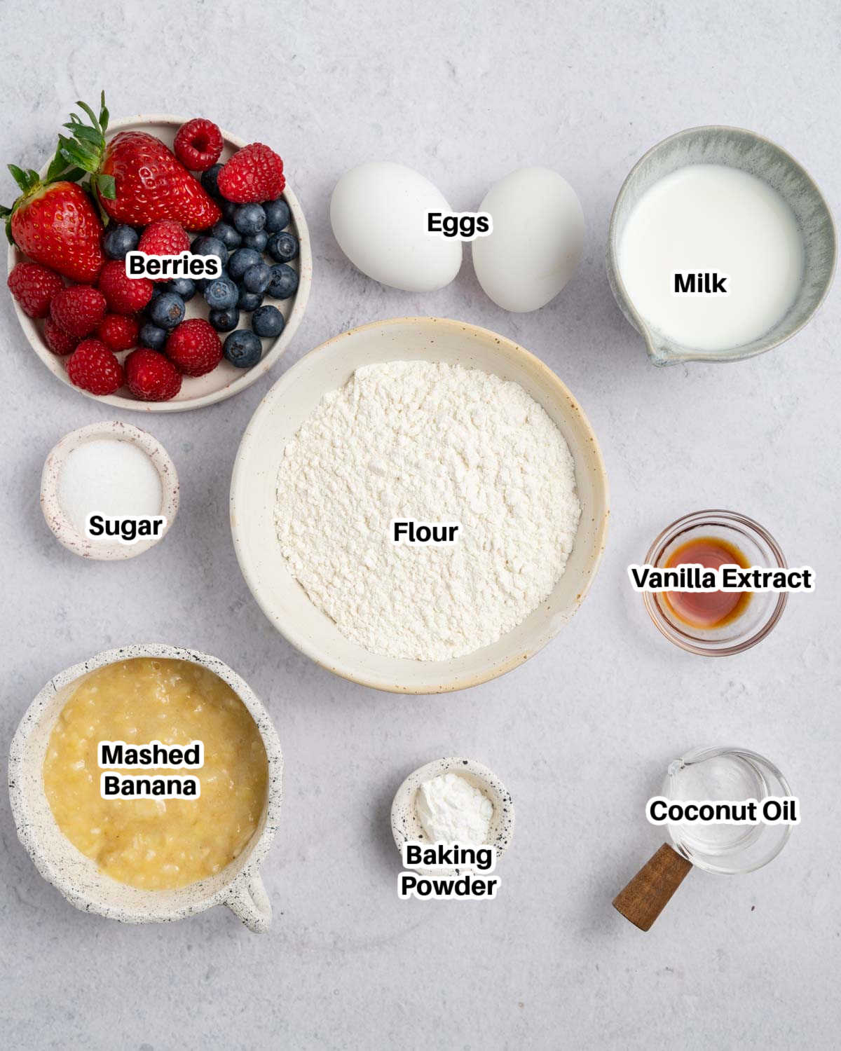 ingredients to make mini pancake muffins with a bowl of berries.