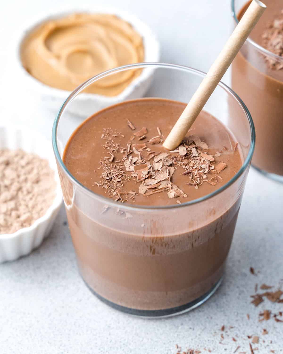 a cup butter chocolate protein shake  topped with chocolate shavings..