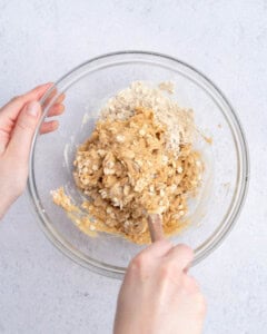hand mixing the peanut butter oat base in a bowl.