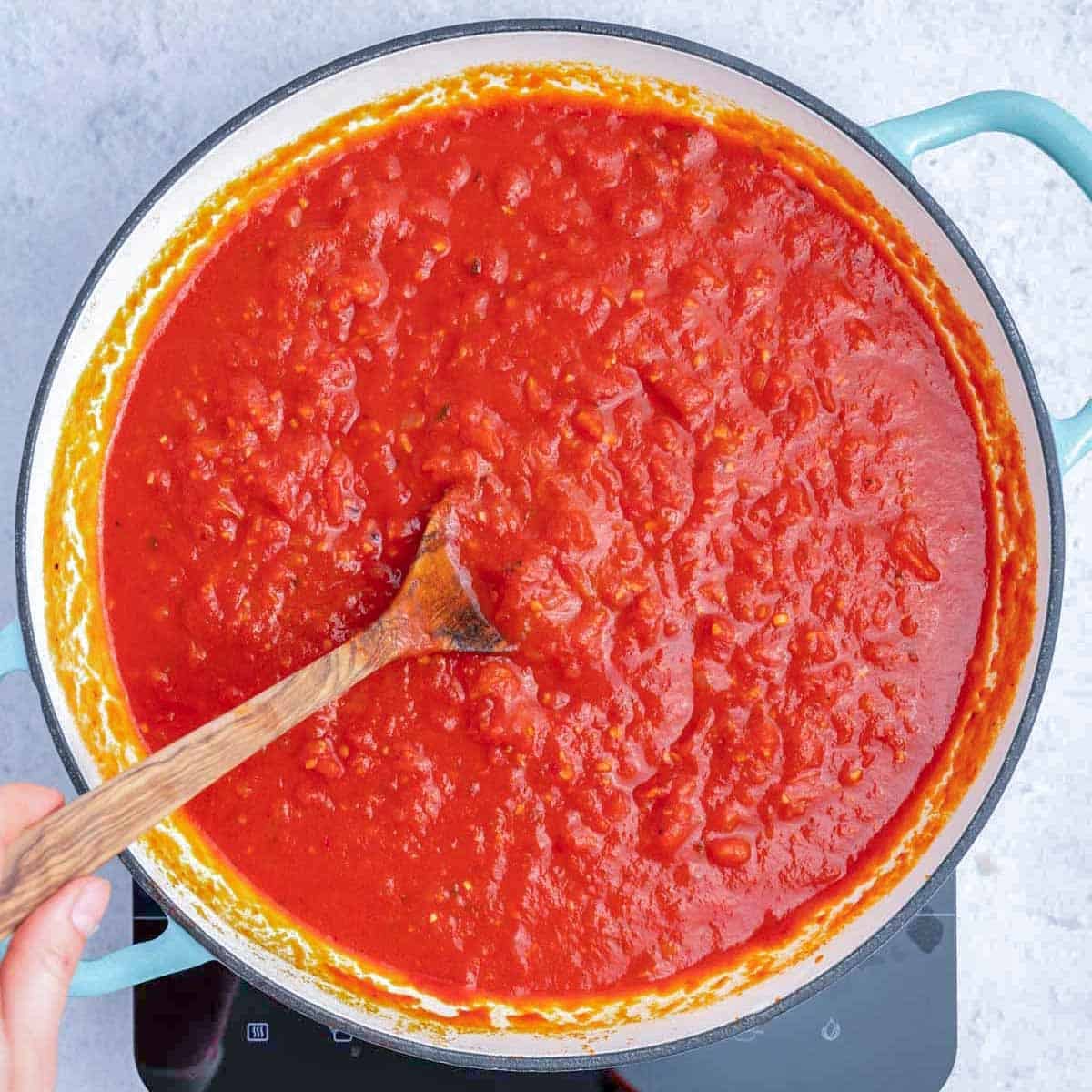 arrabiata sauce in a pan with a spoon in the sauce.