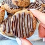 hand holding a cookie drizzled with melted chocolate.