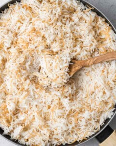 spoon fluffing cooked rice in a pan.