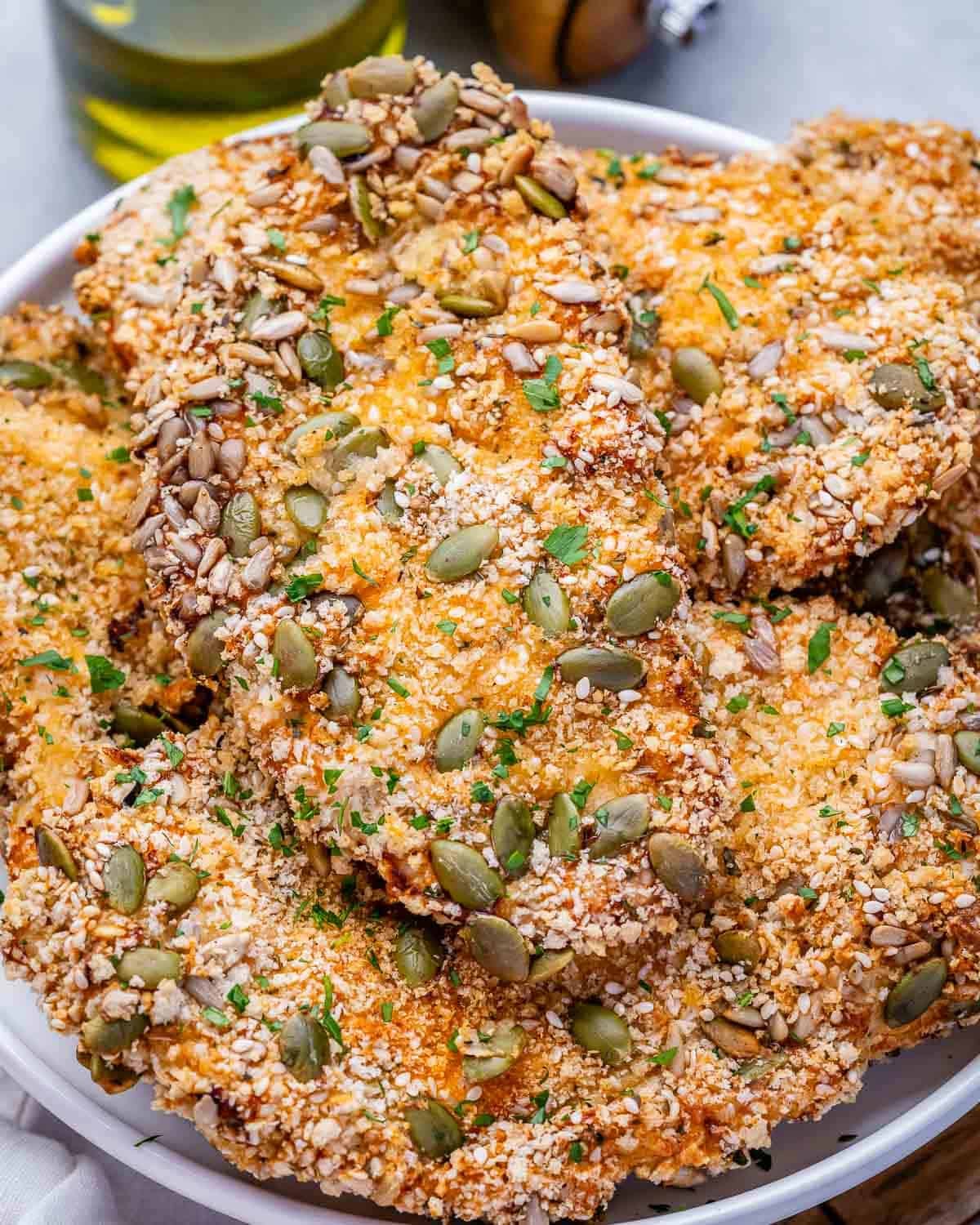 Seeded air fryer chicken cutlets on a white plate.