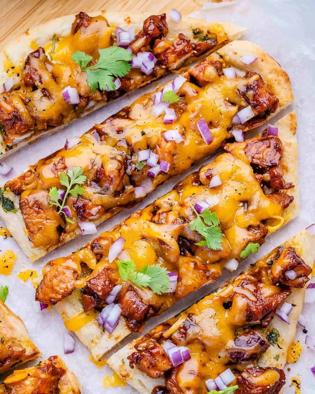 sliced bbq chicken flatbread topped with some chopped cilantro.