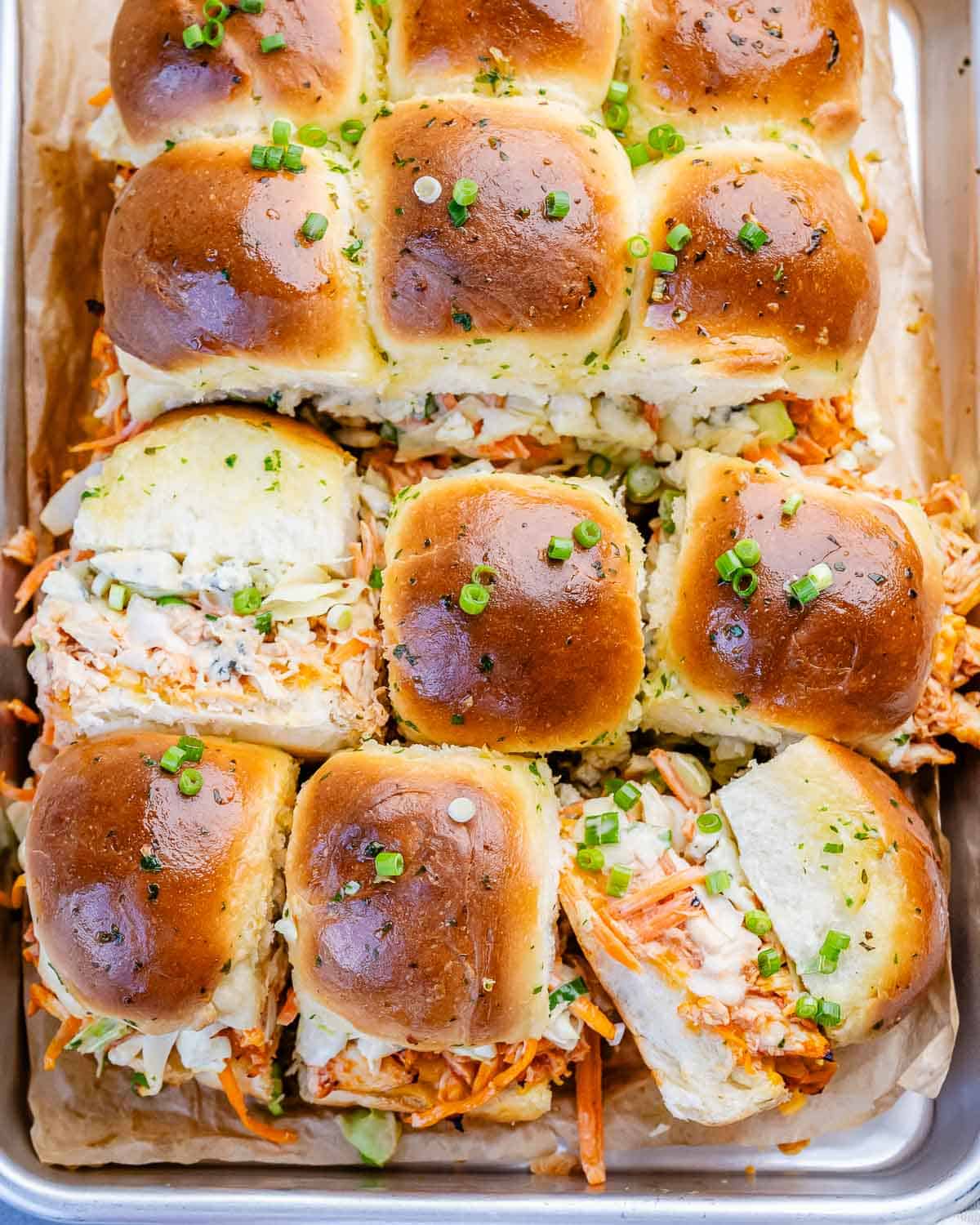 Buffalo chicken sliders with garlic butter on a sheet tray.