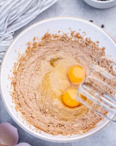 two eggs added over whipped sugar and butter in a bowl.