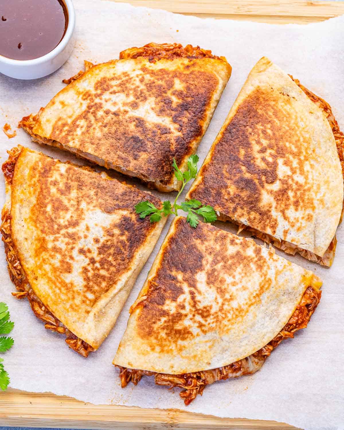 Chicken quesadilla cut into 4 parts on a cutting board.