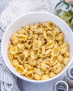 cooked pasta tossed in oil and herbs in a bowl.