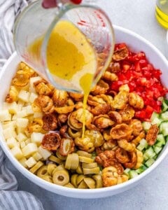 drizzling the dressing over the pasta salad.