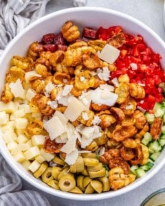 pasta salad topped with shaved parmesan in a round white bowl.