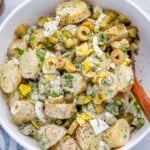 a white bowl with potato salad made with pickles and fresh dill.