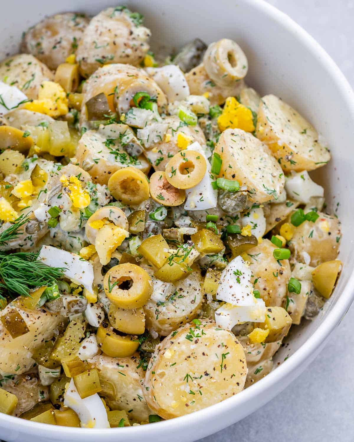 A white bowl with dill pickle potato salad.