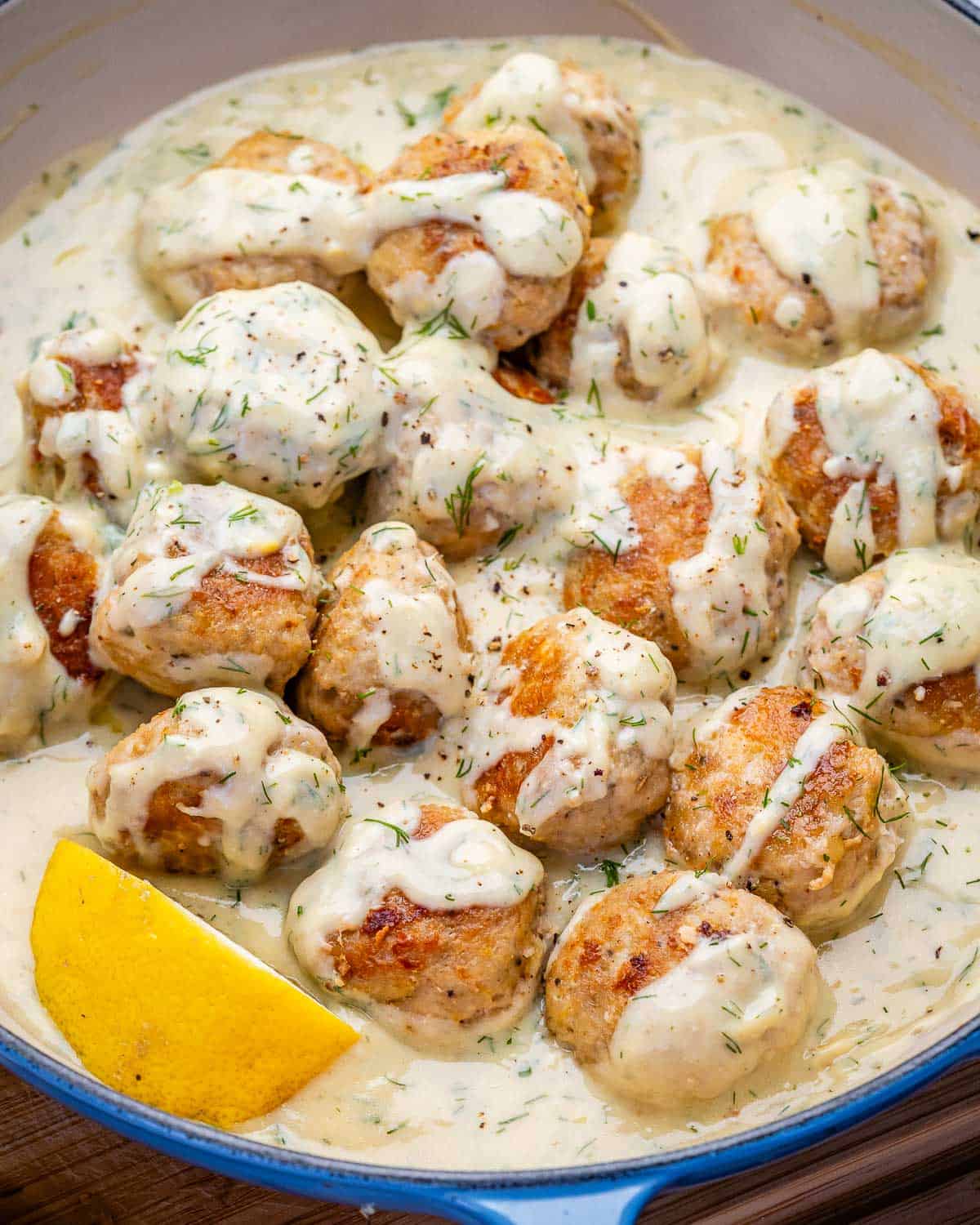 greek chicken meatballs cooked a creamy lemon sauce in a skillet.