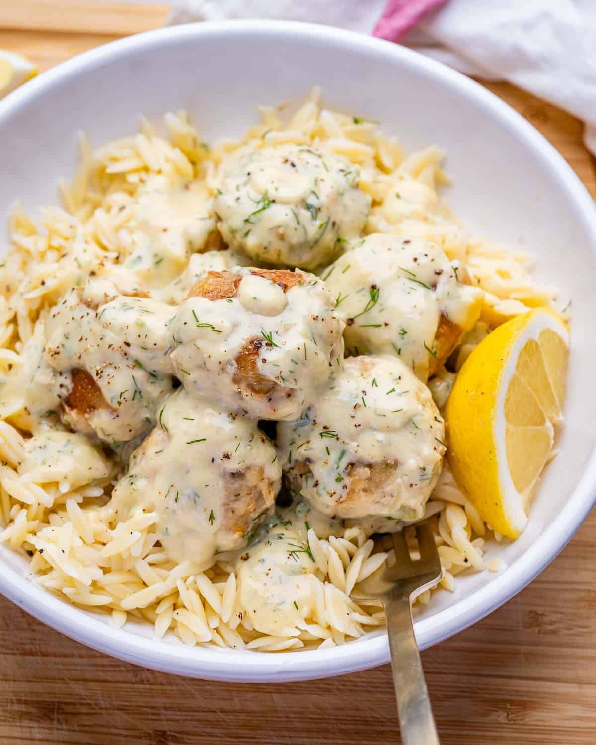 creamy chicken meatballs served over cooked orzo in a bowl.
