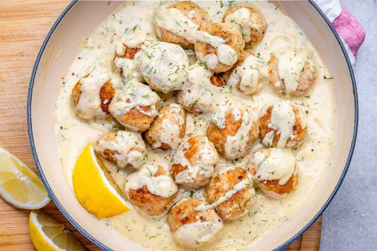 Chicken meatballs cooking in a creamy lemon sauce.