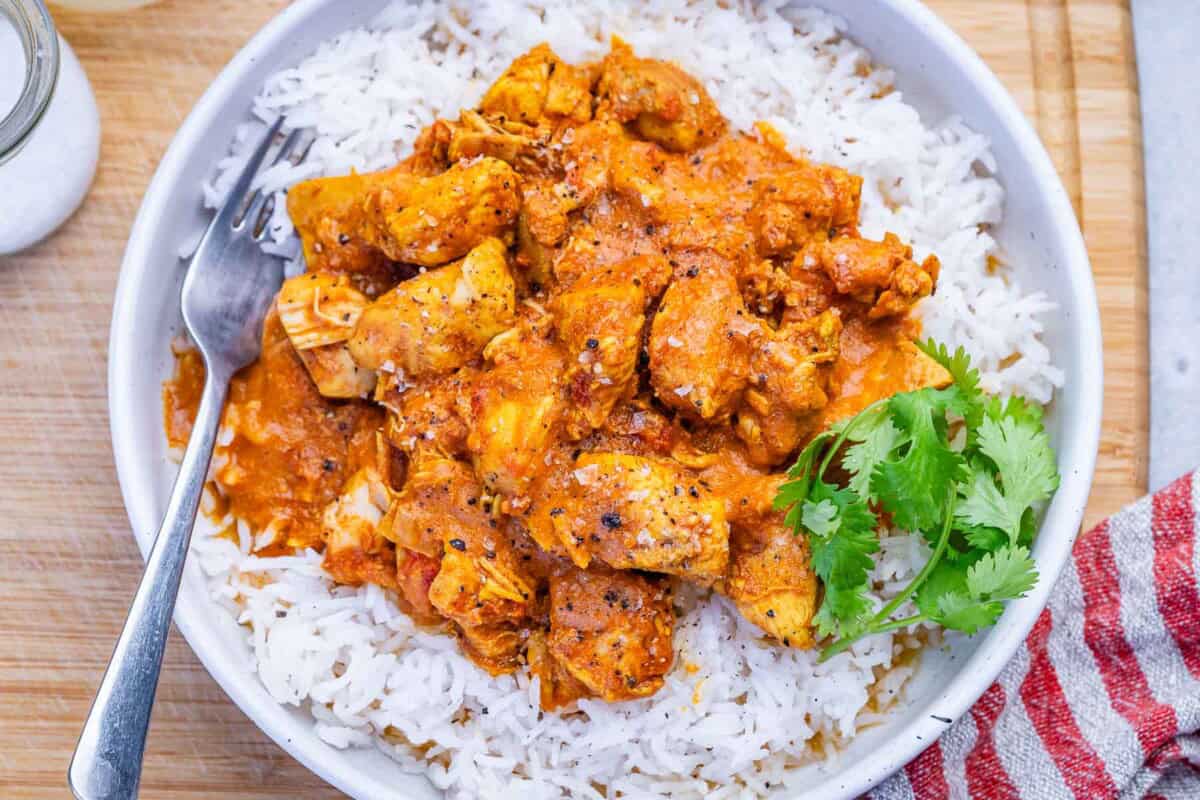 Butter chicken served over a bowl of rice.