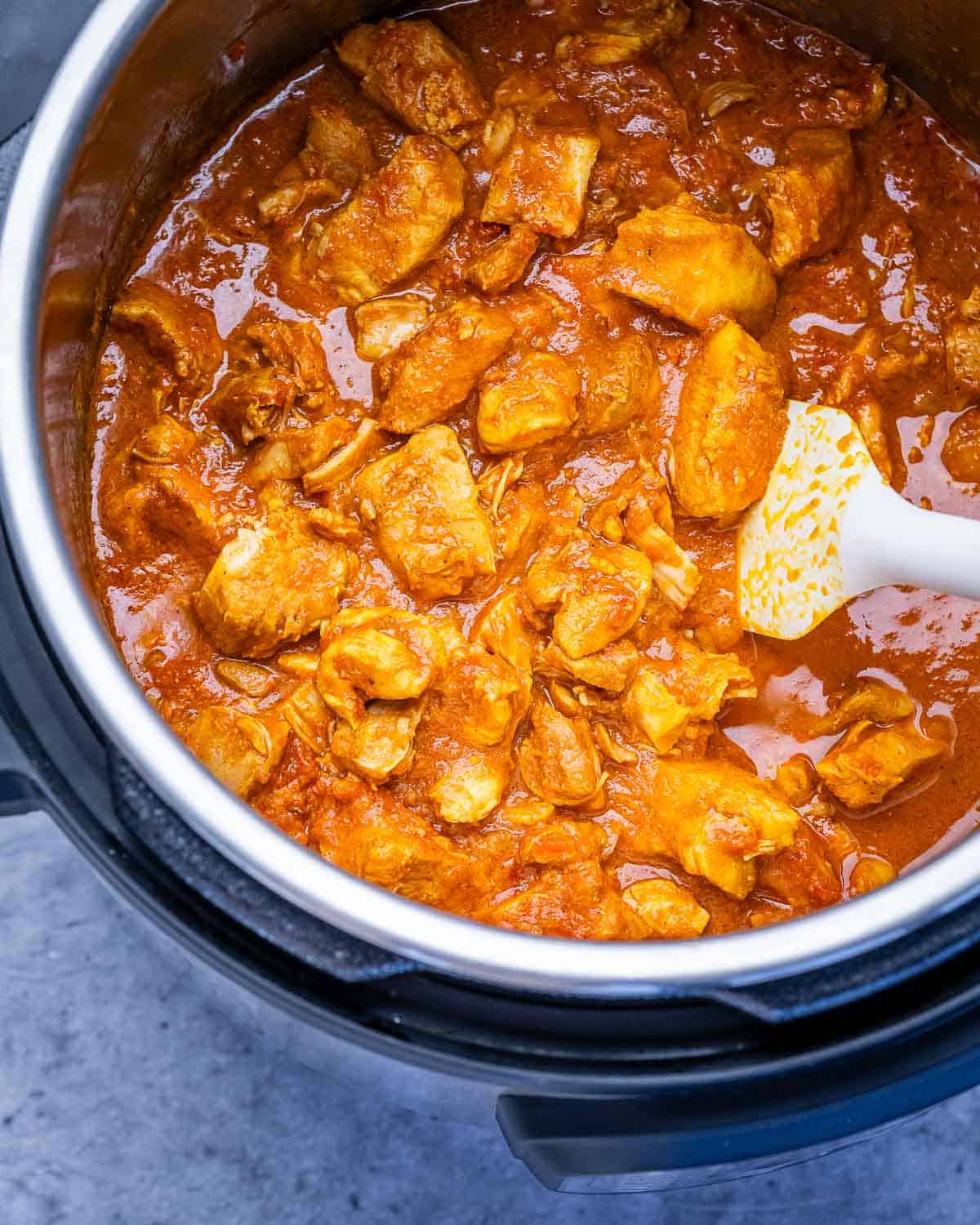 Butter chicken in an instant pot with a white spatula.
