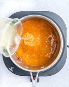 adding broth to the sauce in the pan.