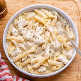 chicken alfredo with penne pasta served in a round white bowl.