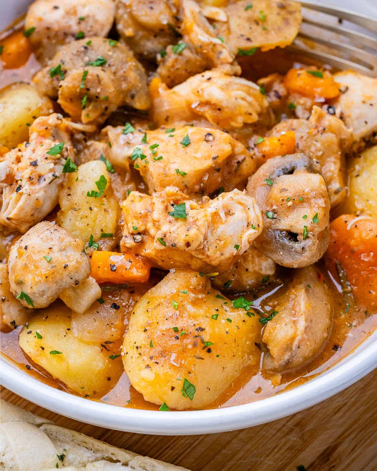 A closeup of crockpot chicken stew in a white bowl.