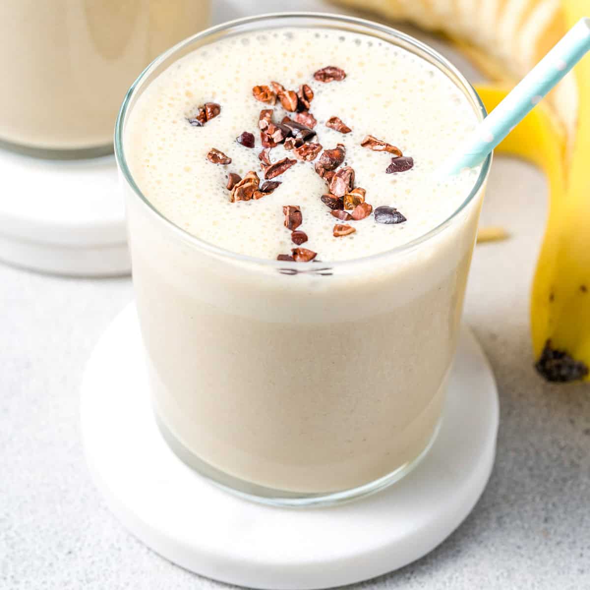 a glass with protein shake topped with cocoa nibs.