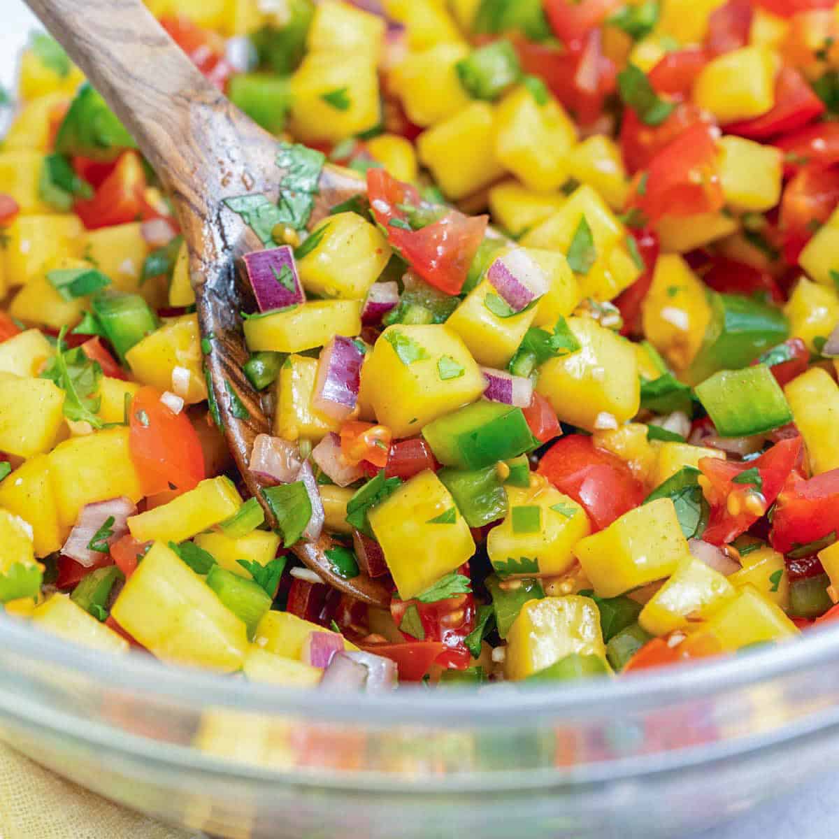 a bowl with mango pico de gallo and a spoon in the bowl.