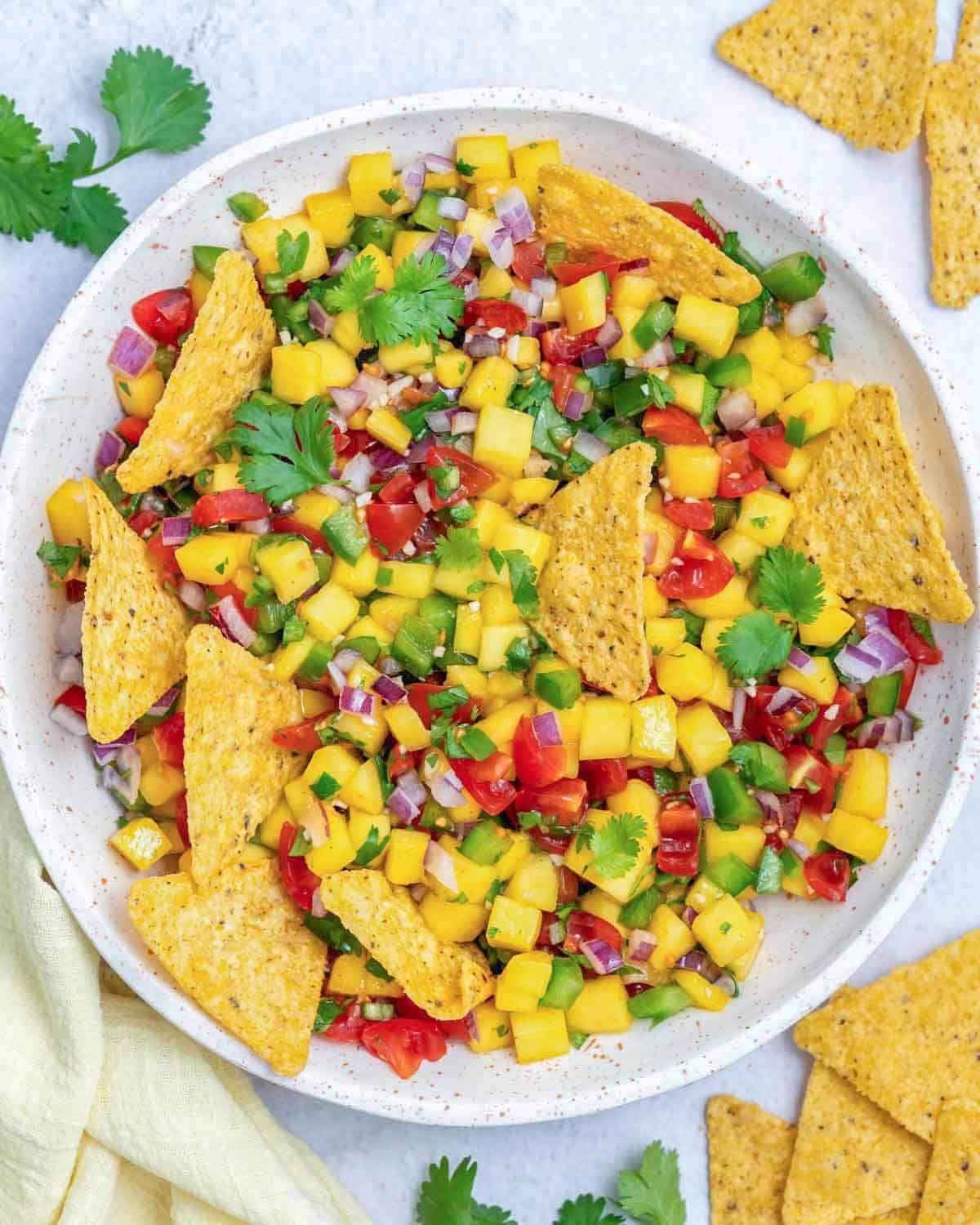 a bowl of mango pico de gallo with tortilla chips in it.